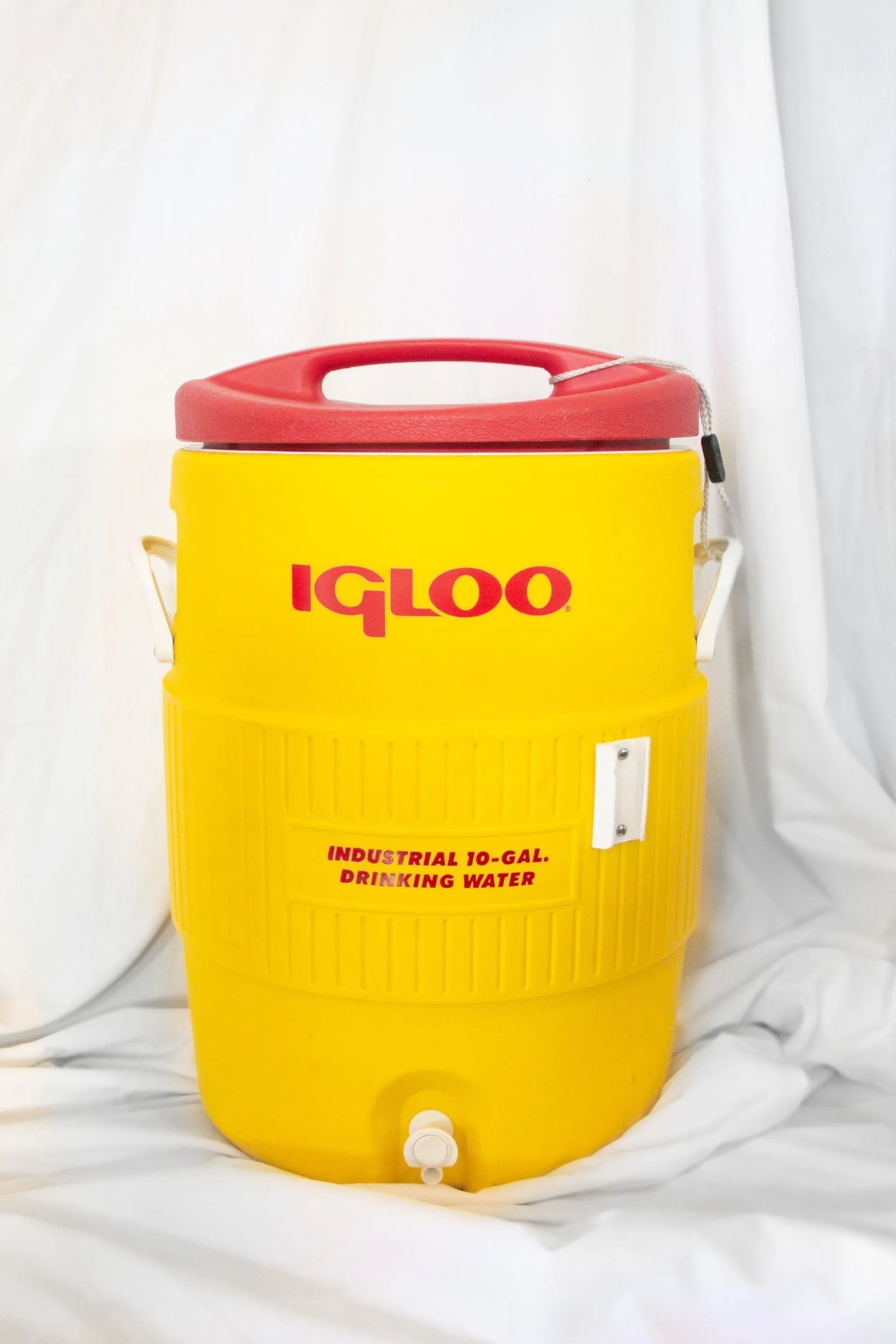 Yellow Igloo water cooler with a red lid and logo. It has a spout and a handle.