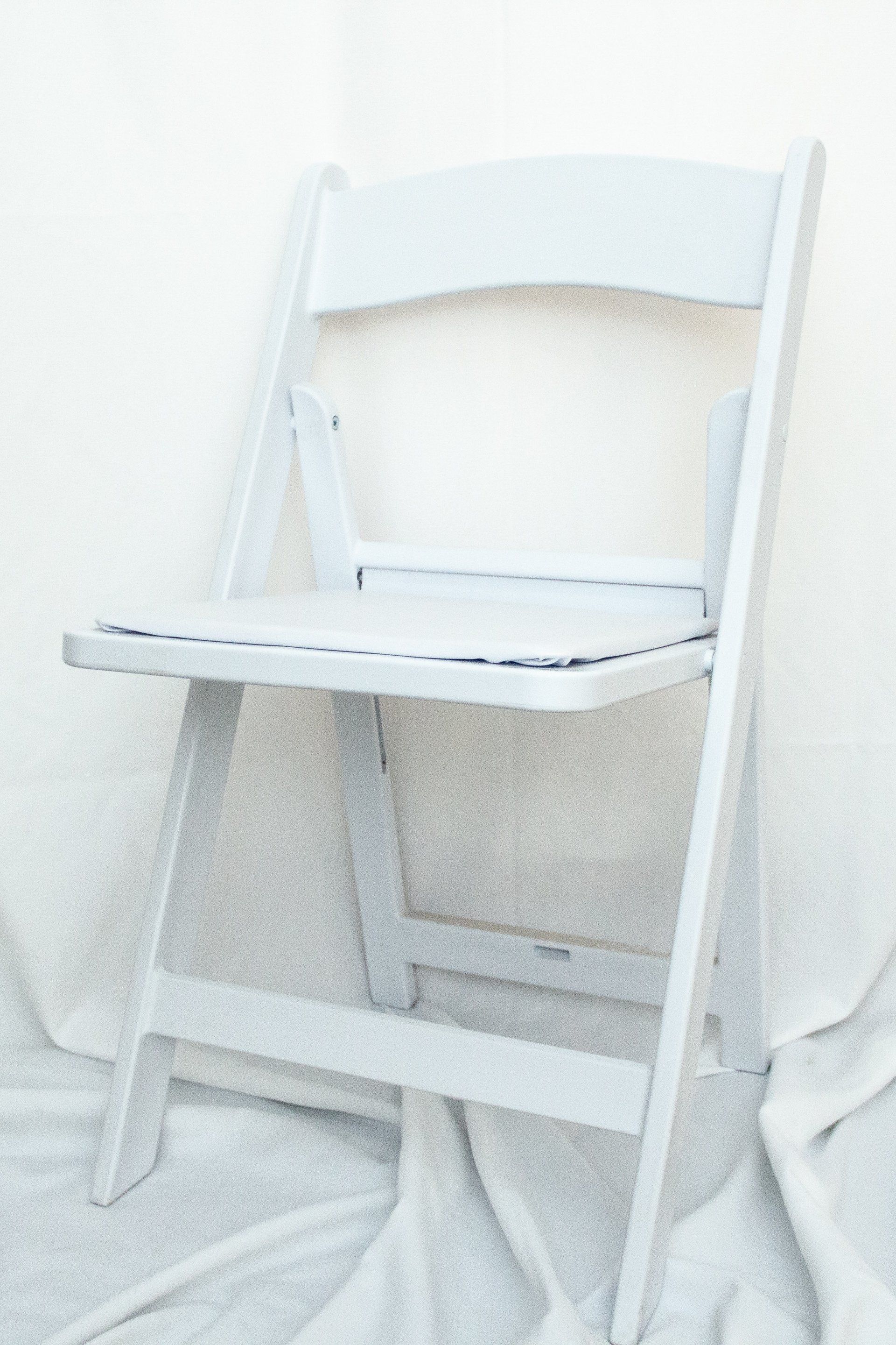 White folding chair on a white surface.