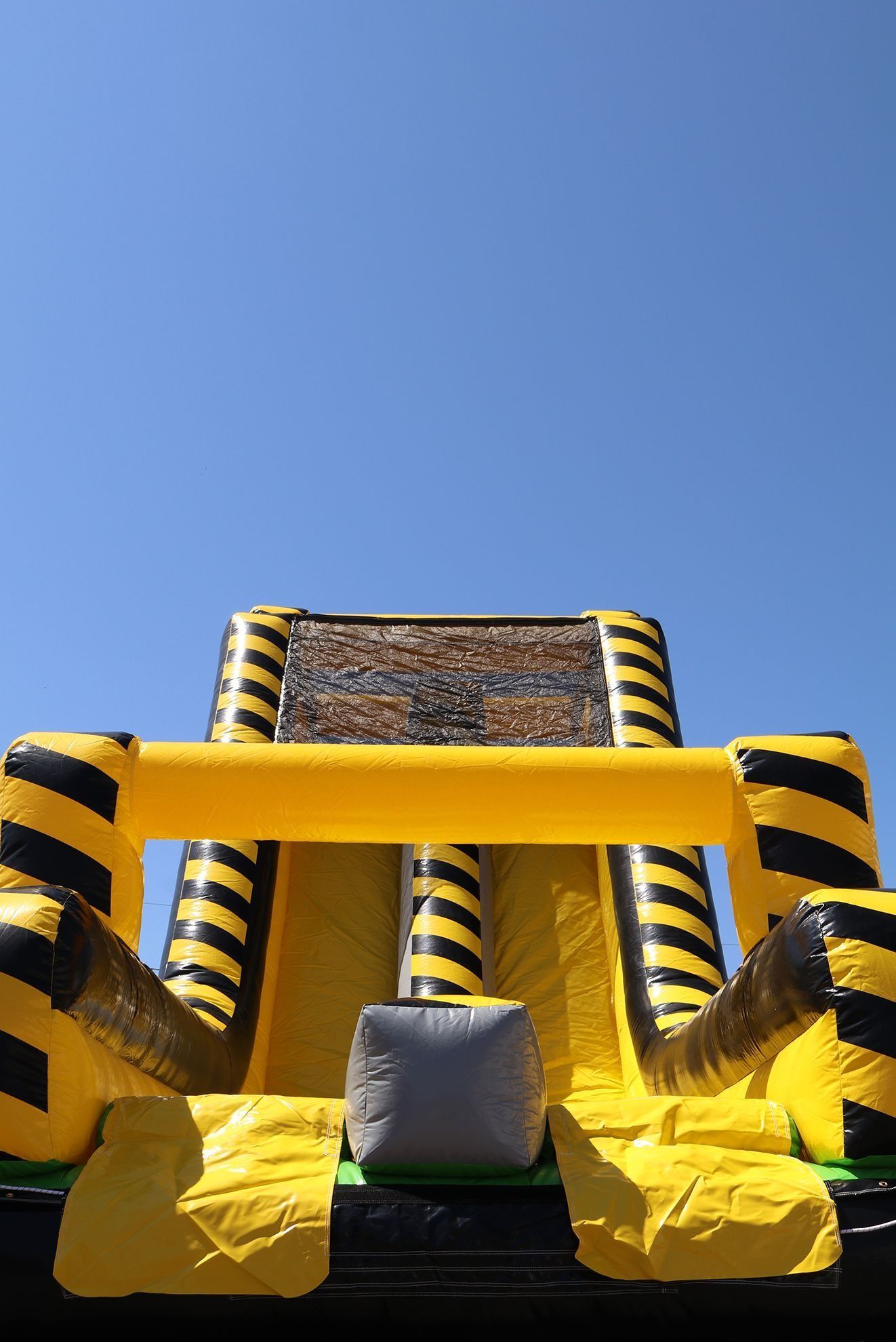 Yellow and black inflatable slide against a clear blue sky.
