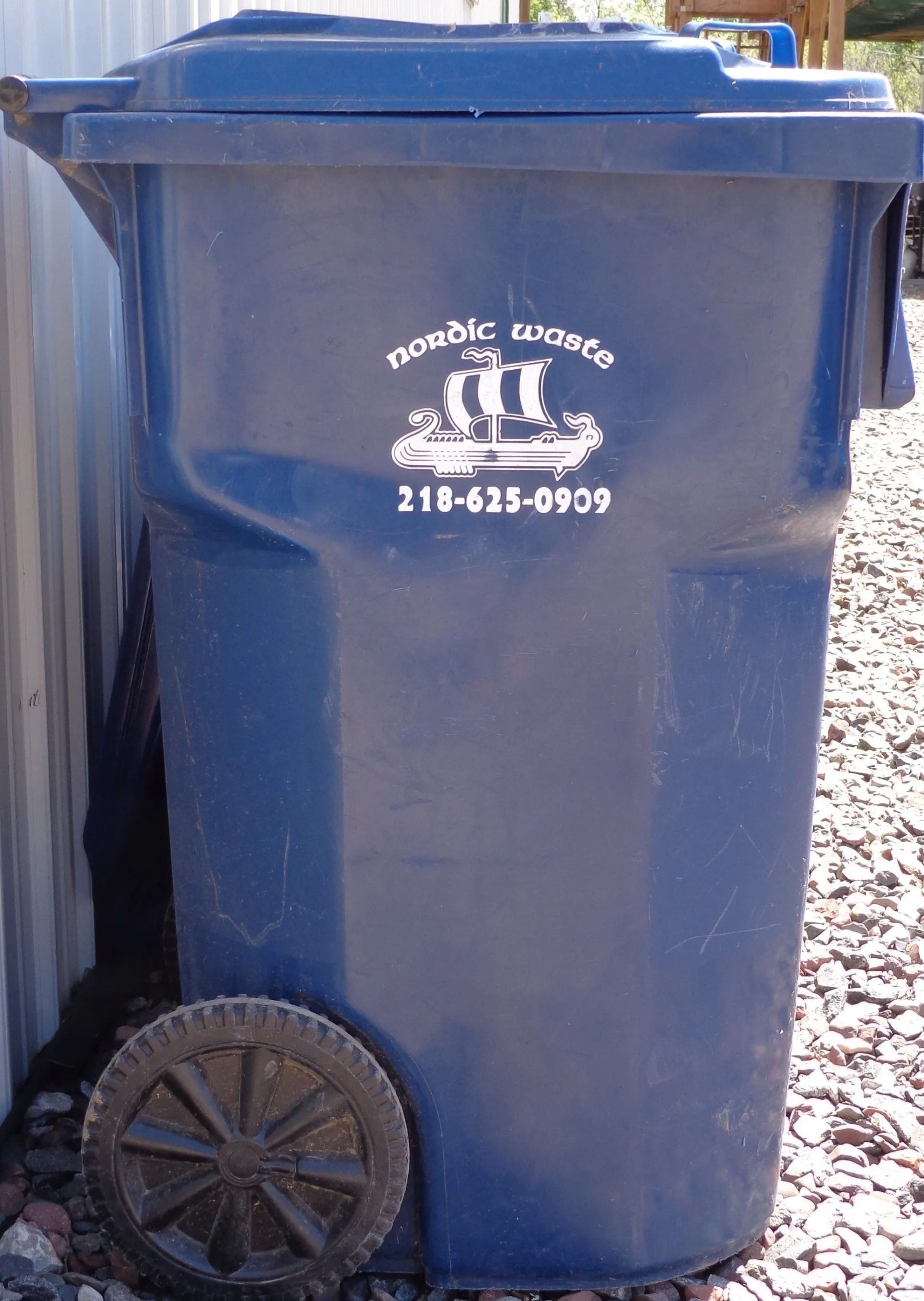 Blue trash can with a lid, wheel, and a logo with a ship.