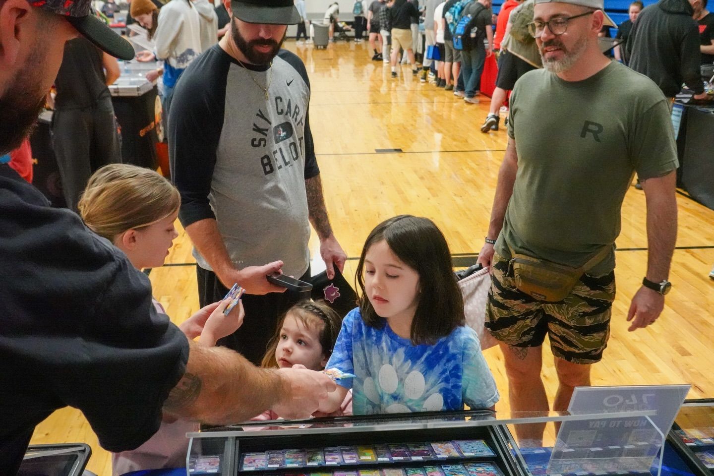 People at a gymnasium table interacting with children during an event