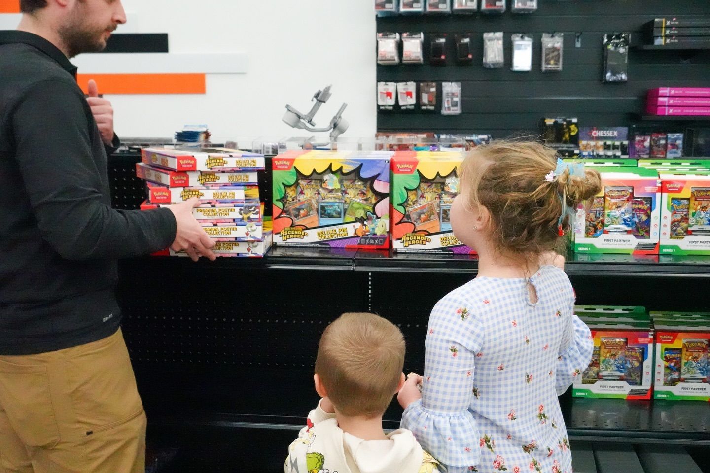 Three people browse colorful toy boxes in a store aisle.