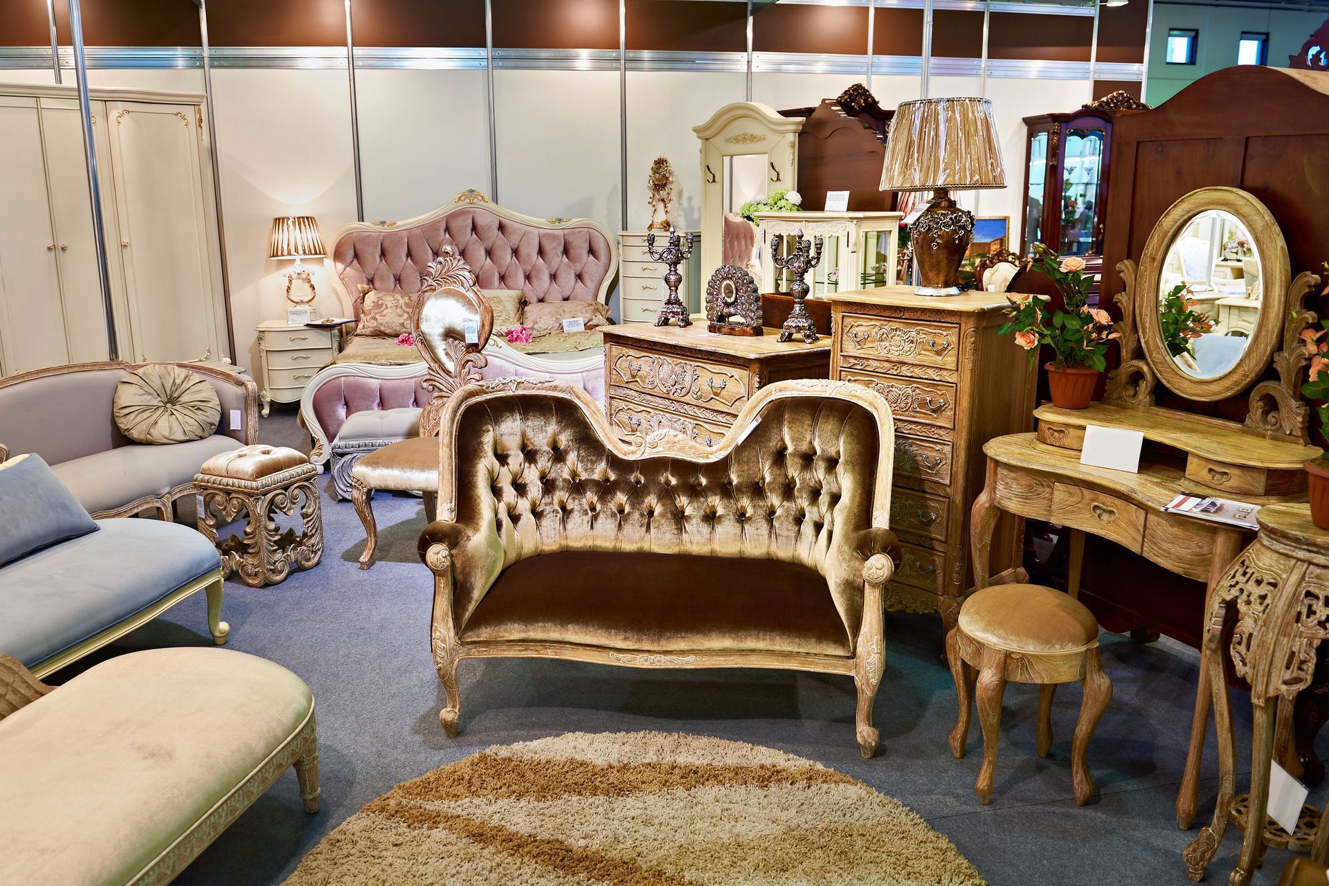Exhibition booth with ornate antique furniture, including sofas, dressers, and a vanity.