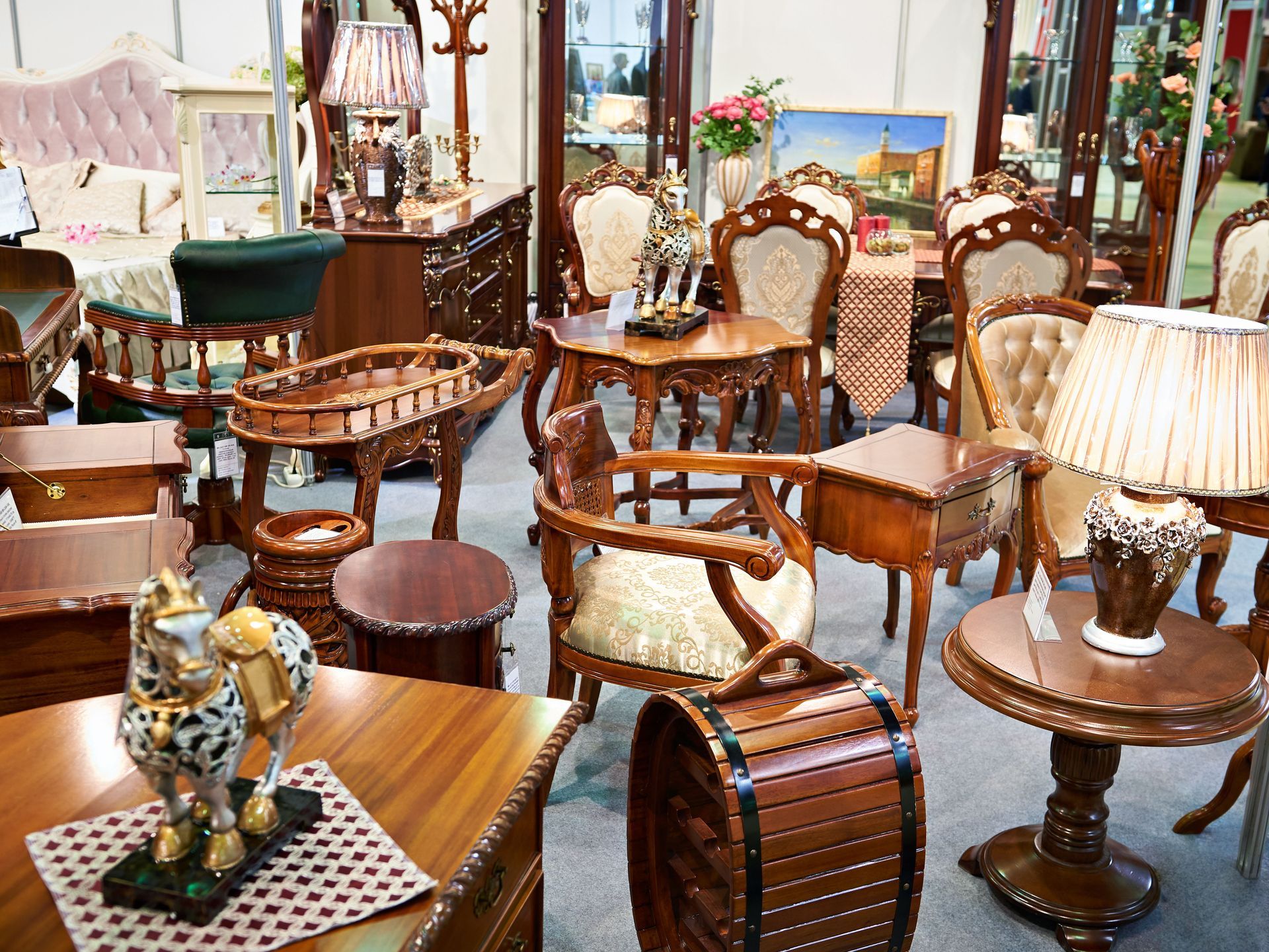 Display of ornate wooden furniture in a store, including chairs, tables, and decorative pieces.