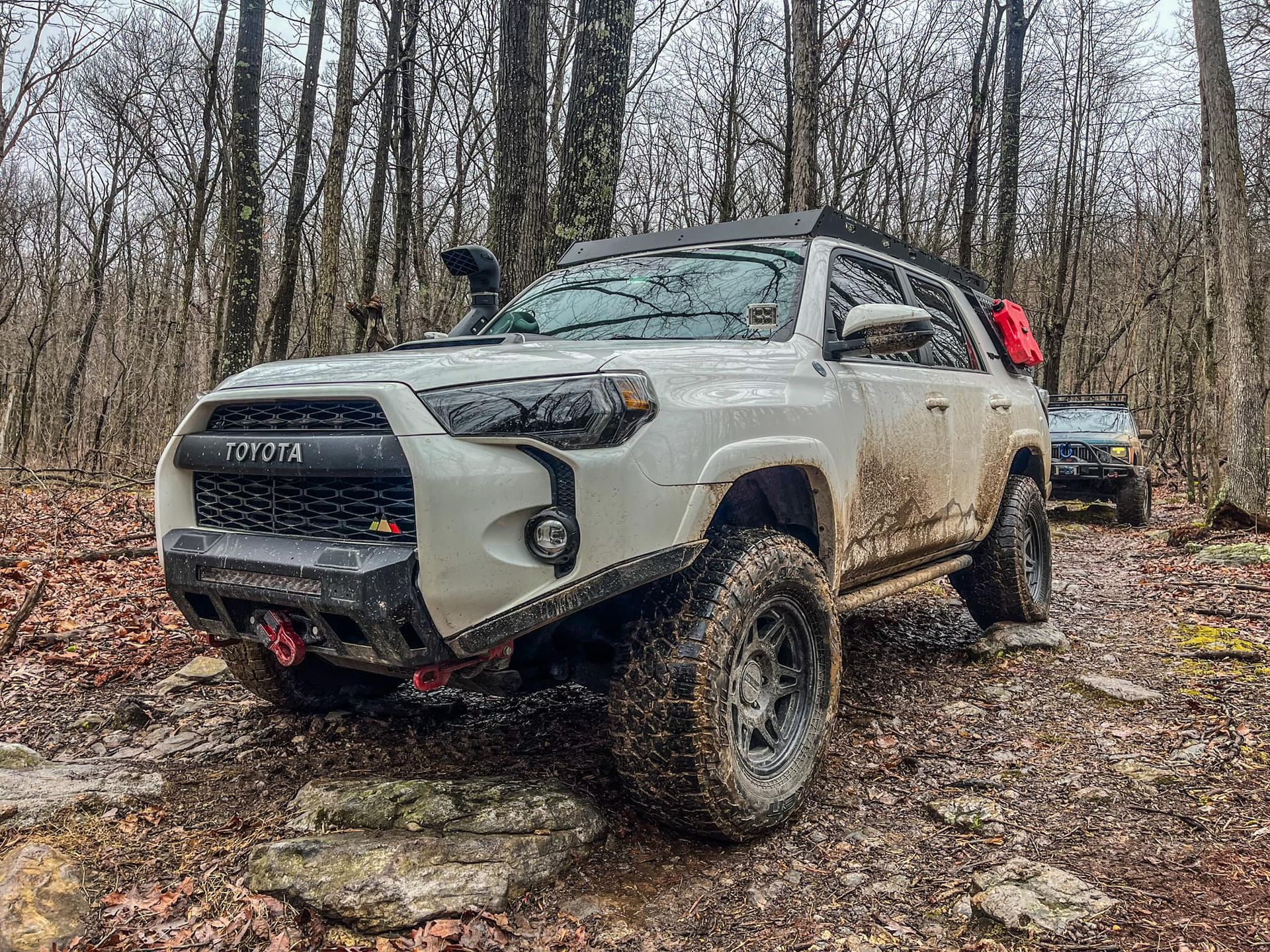 A white toyota 4runner parked on a rocky trail in the woods