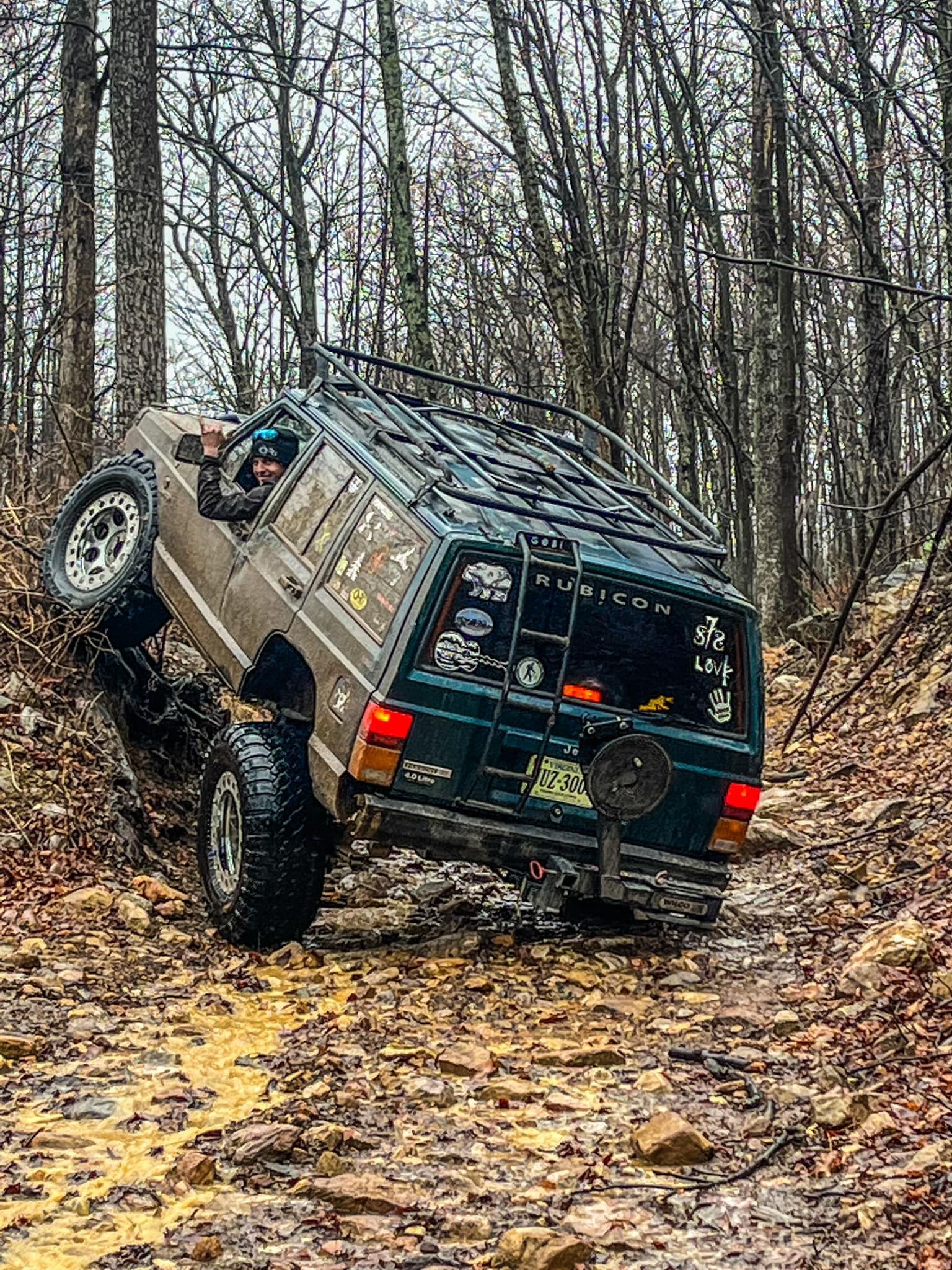A jeep driving down a muddy trail in the woods