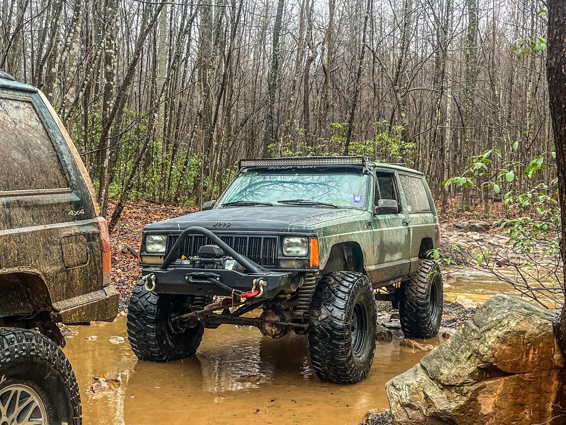 A jeep parked in the mud in the woods