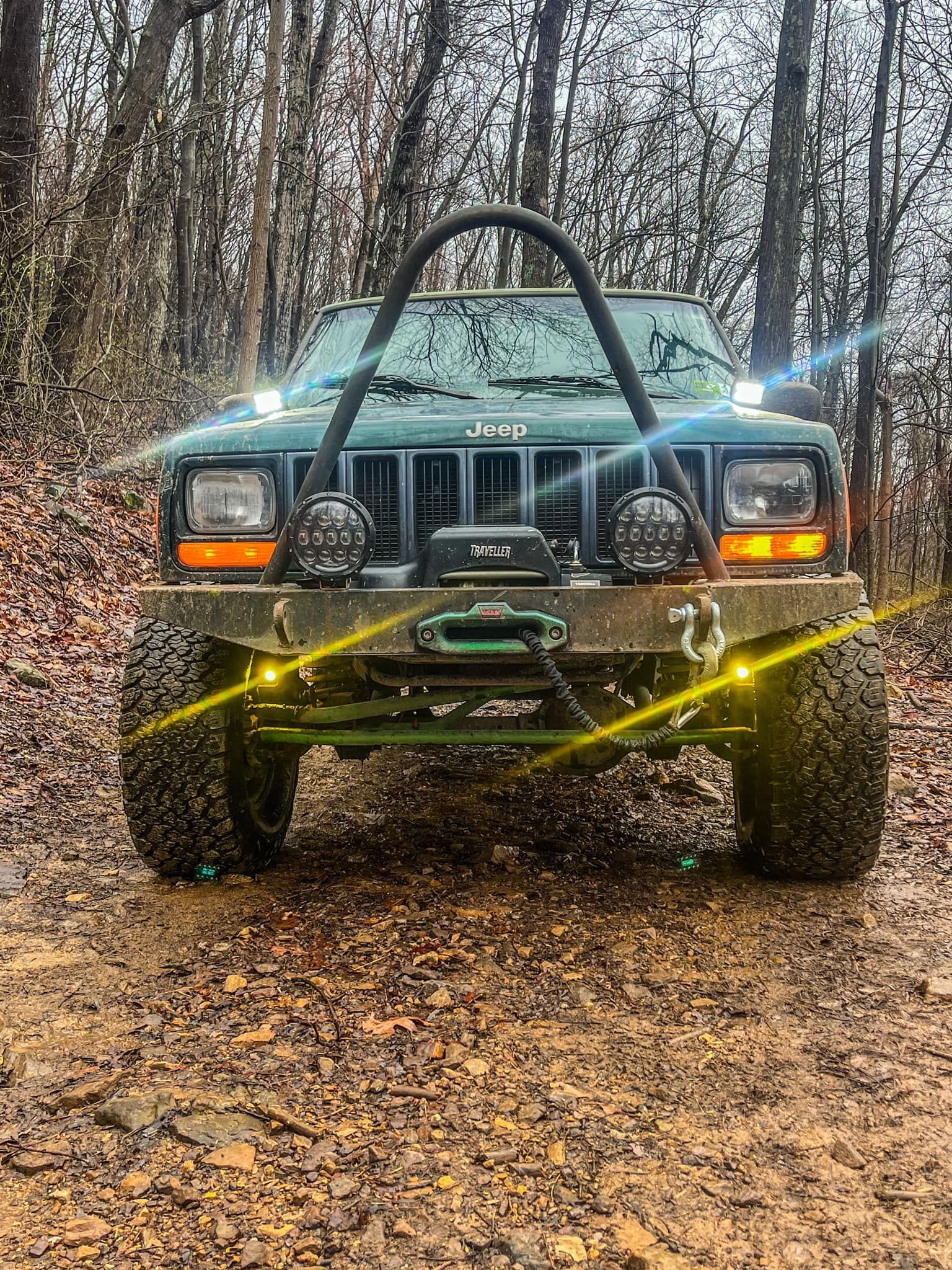 A green jeep parked on a dirt road in the woods