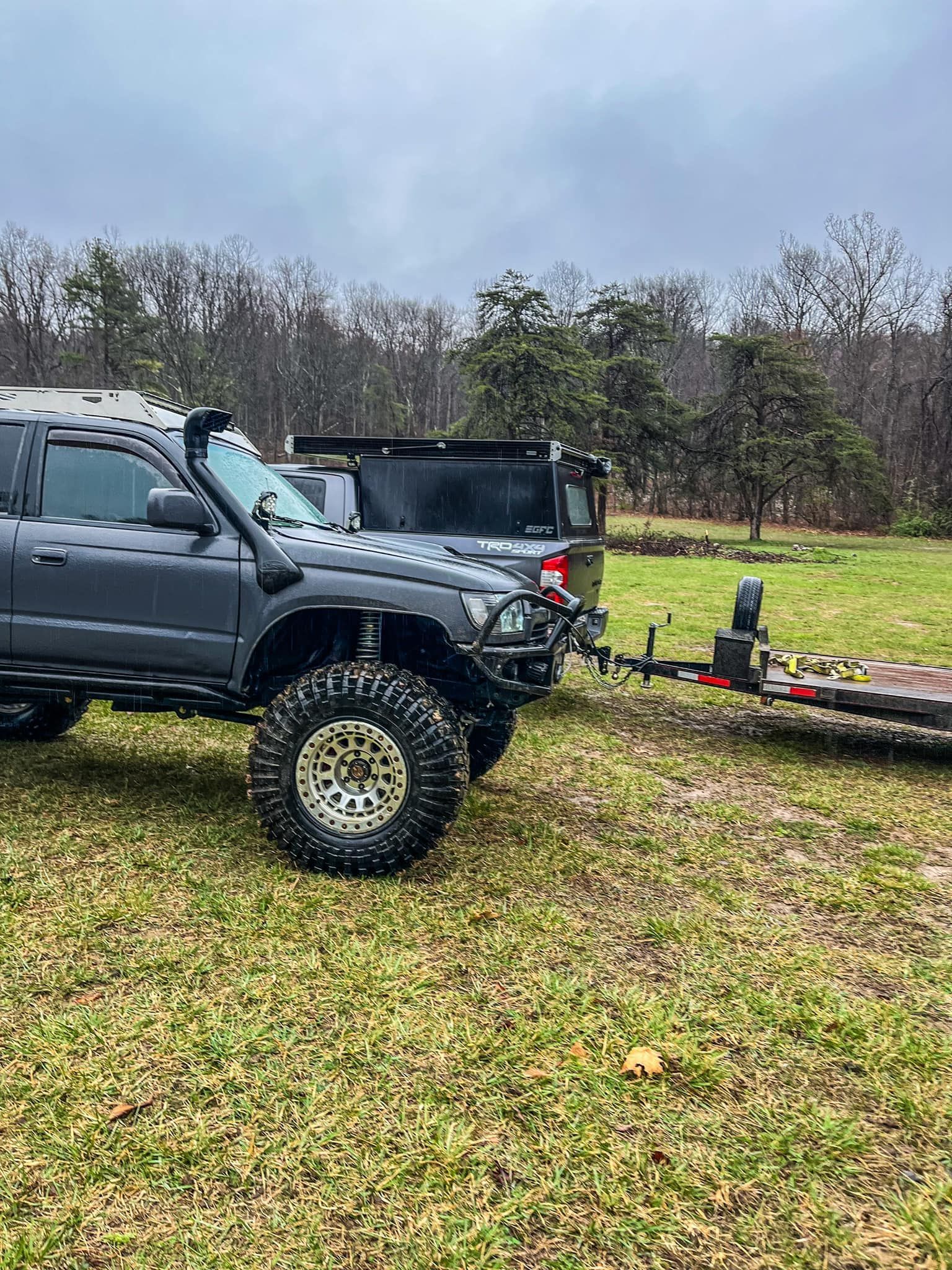 A truck towing a trailer in a grassy field