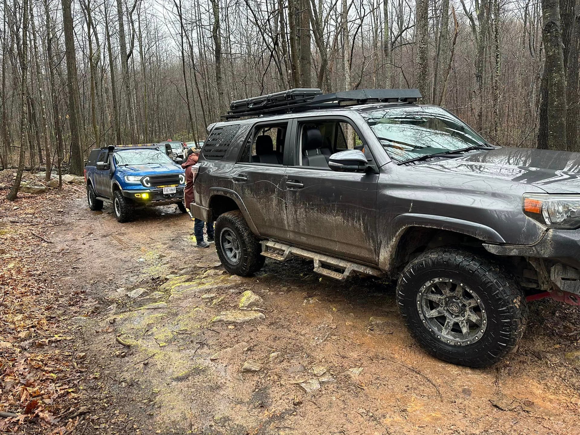 Two cars parked on a dirt road in the woods