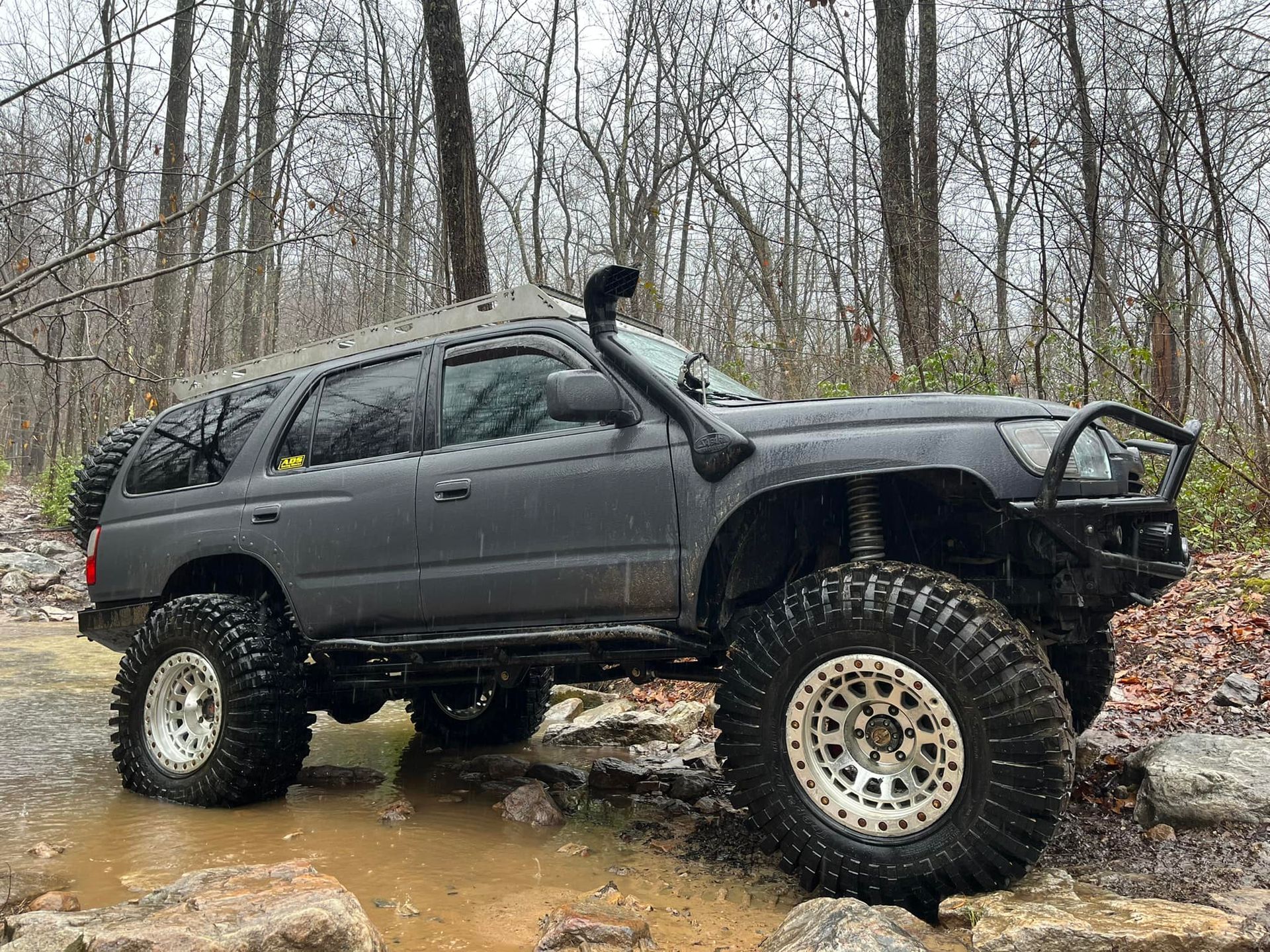 A Toyota 4runner parked in the mud in the woods