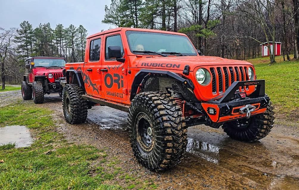 Two jeep wranglers parked next to each other on a dirt road
