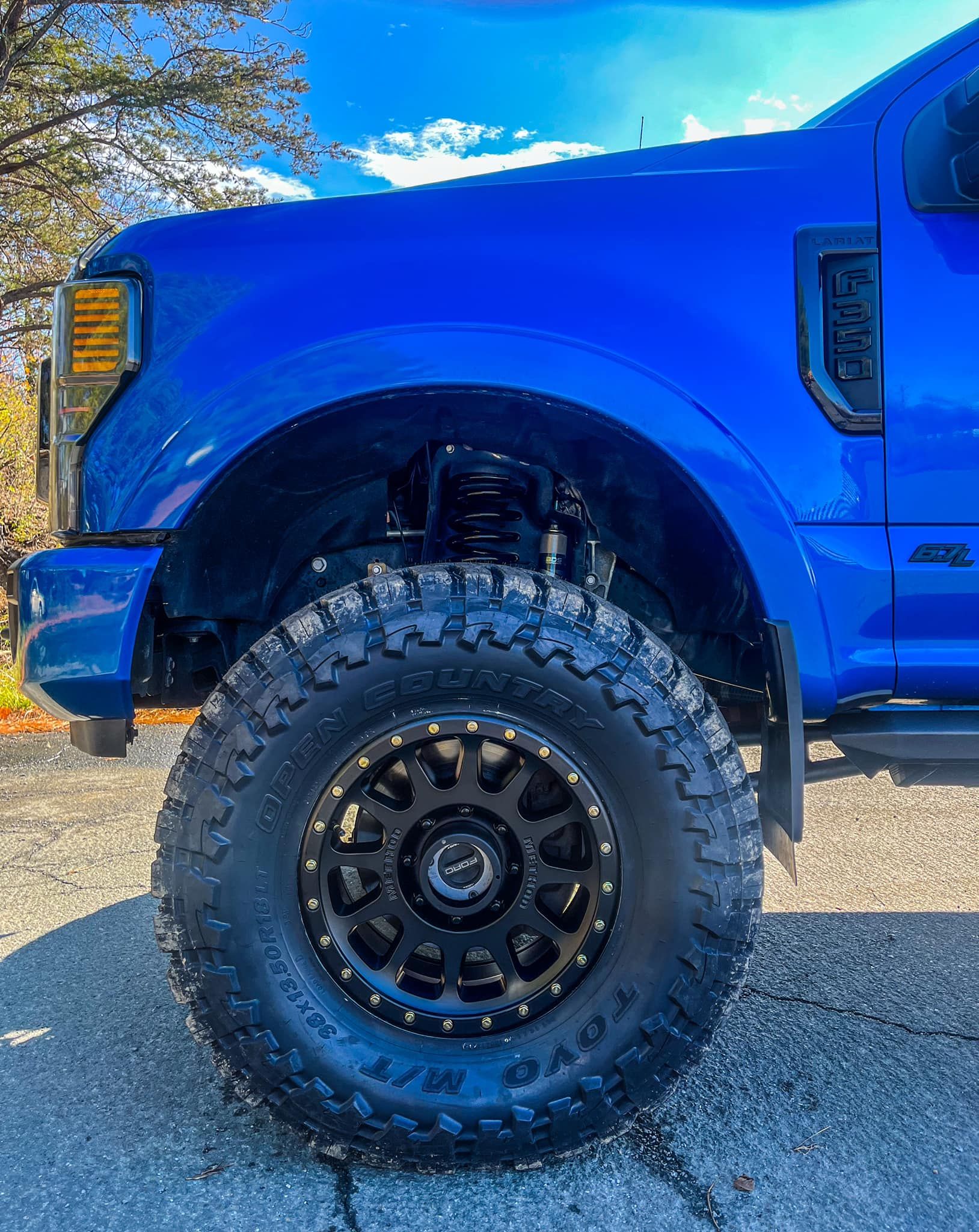 a blue truck with black wheels and tires is parked on the side of the road