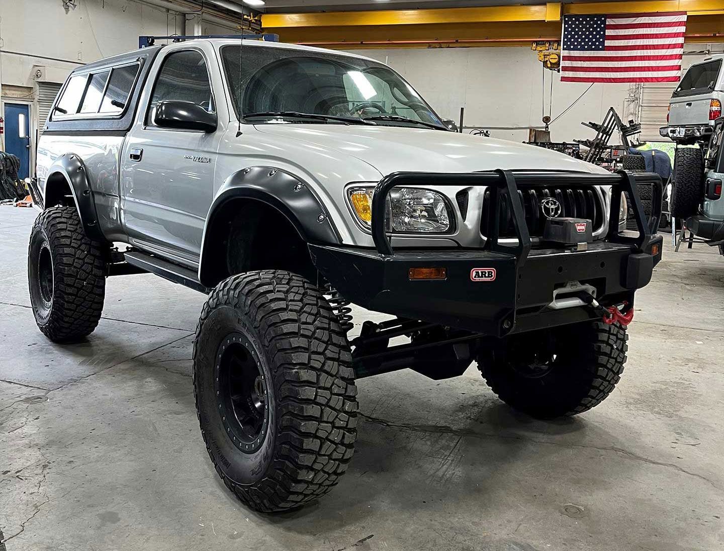 white Toyota truck with a solid bumper and huge tires