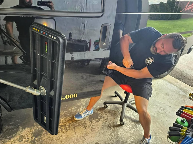 Man using a weight machine in a gym, leaning sideways with a concentrated expression.