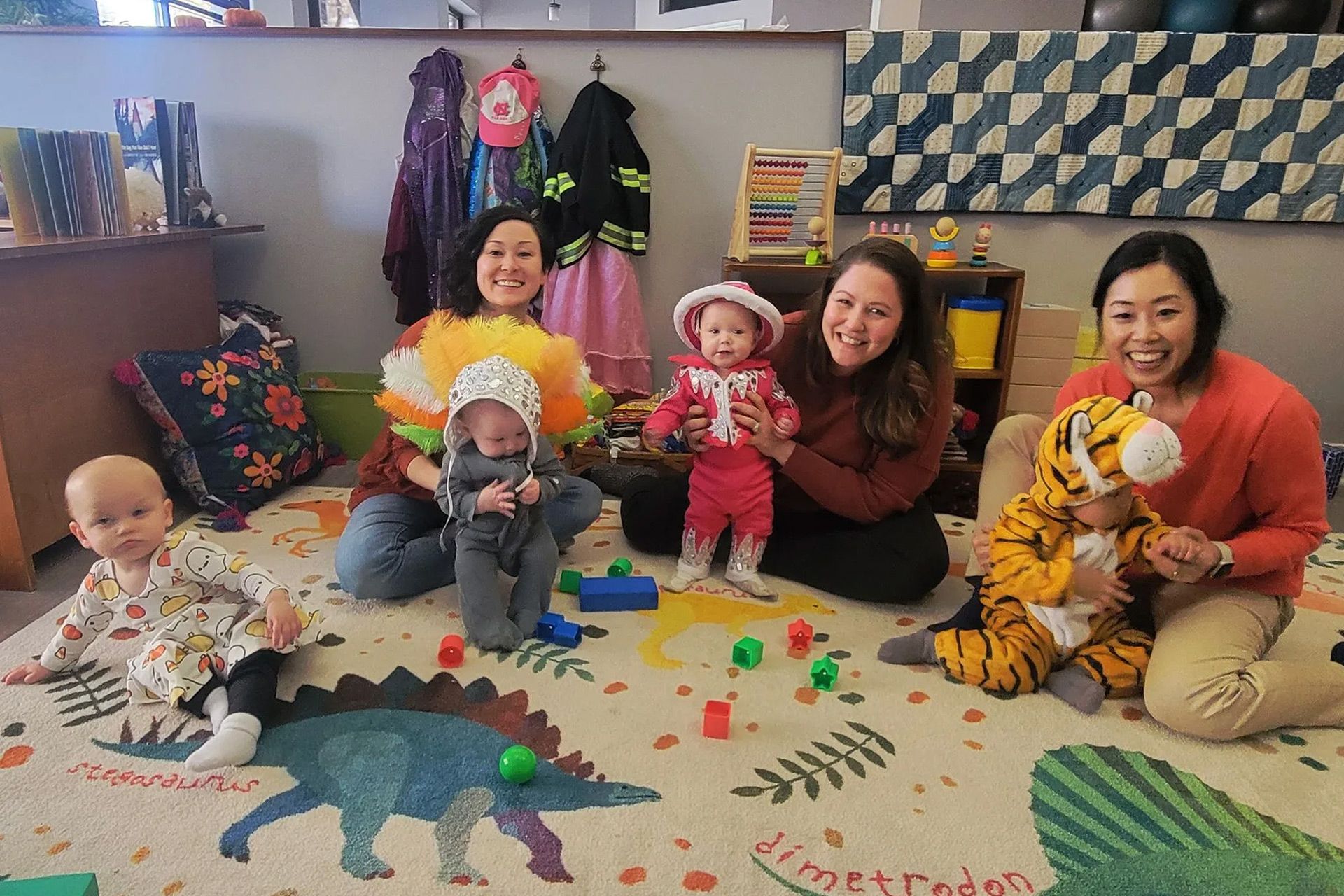 a group of women and babies are sitting on the floor playing with toys