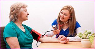 Young nurse measures senior the blood pressure
