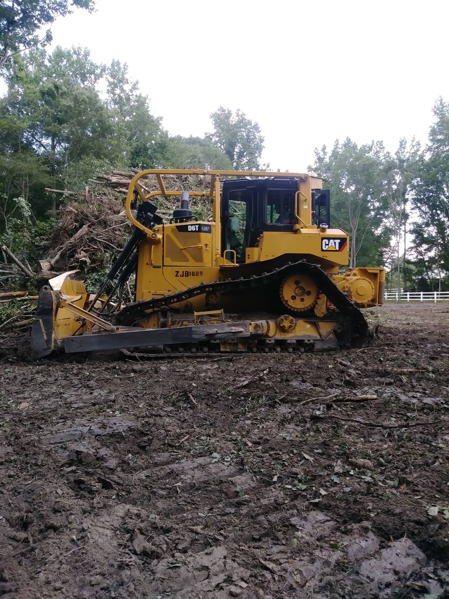 Yellow Caterpillar bulldozer clearing debris on a muddy construction site.