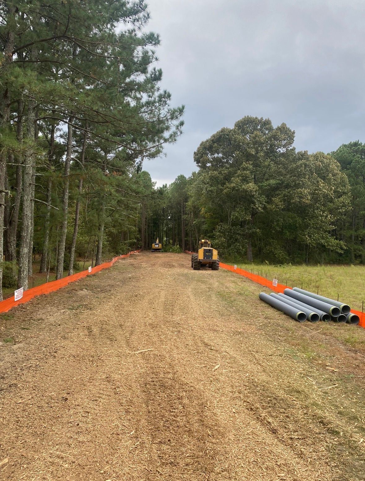 Yellow excavator digging dirt on a roadside under a blue sky.