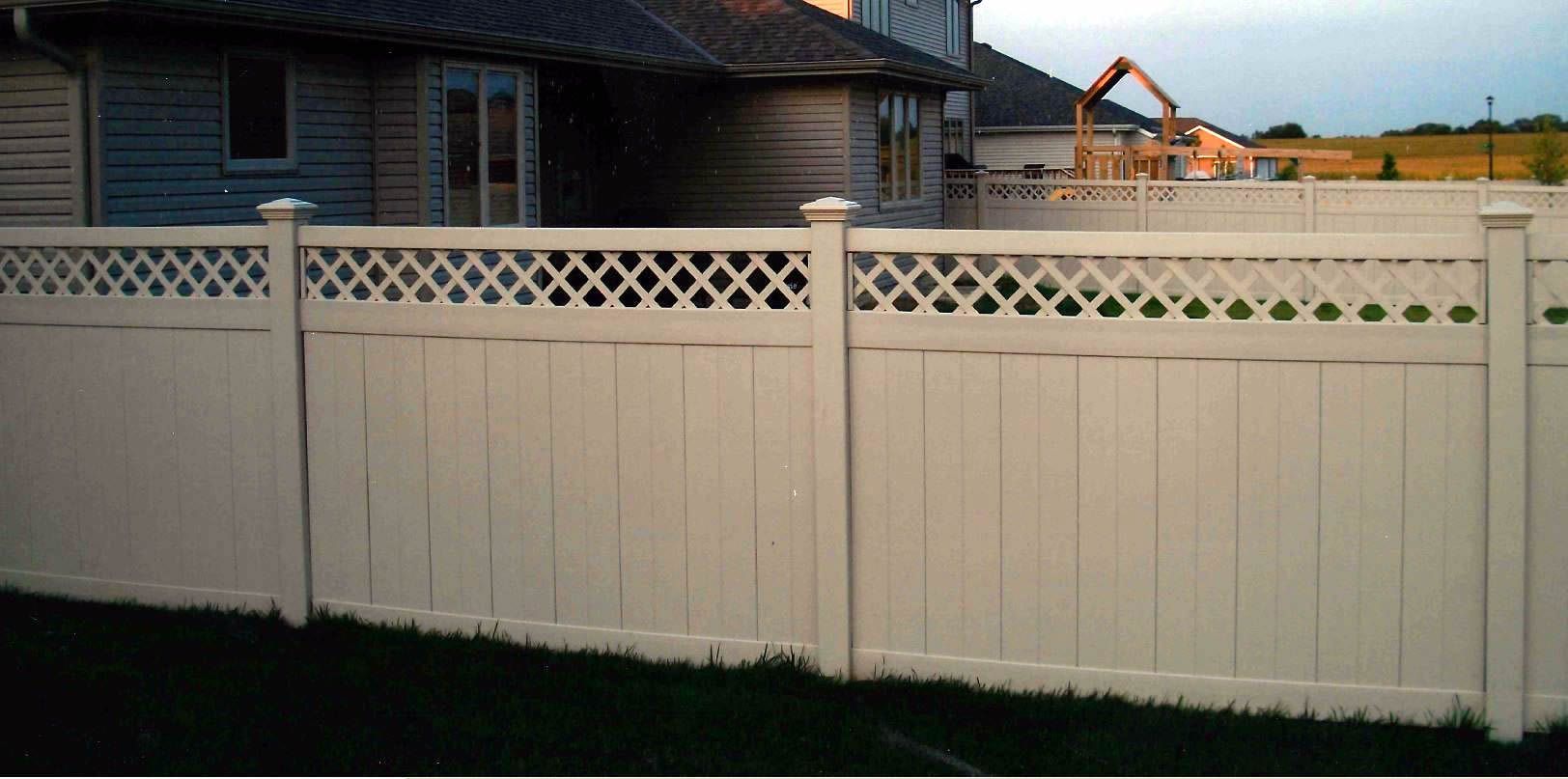 White vinyl fence with lattice top in front of a house.