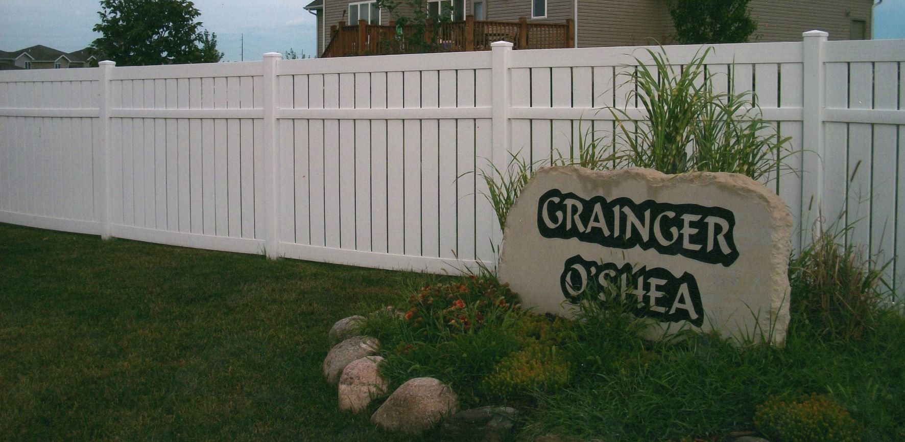 White picket fence with a rock sign that reads 