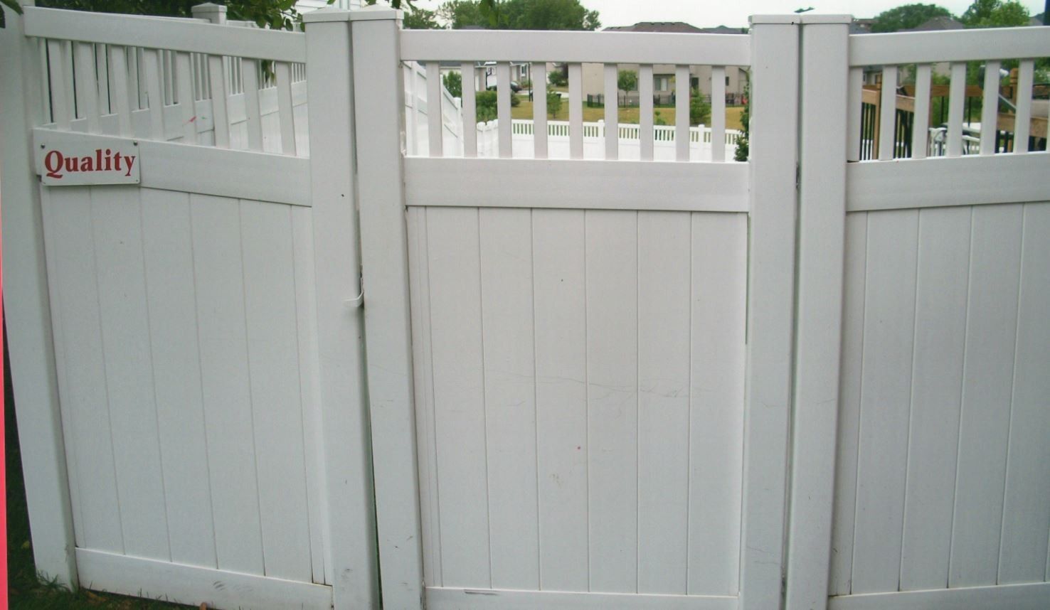 White vinyl fence with gate, in outdoor setting. 