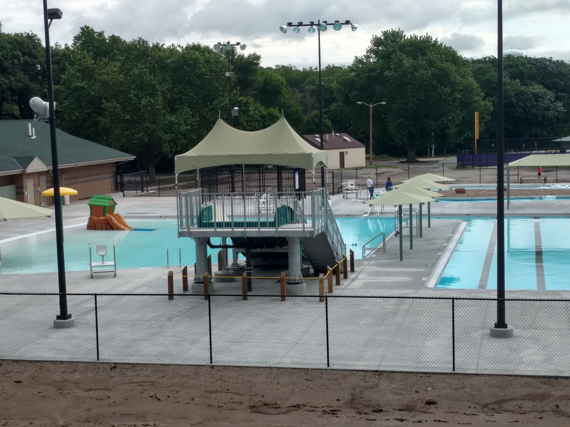 Public swimming pool with a diving platform, water slides, and shade structures.