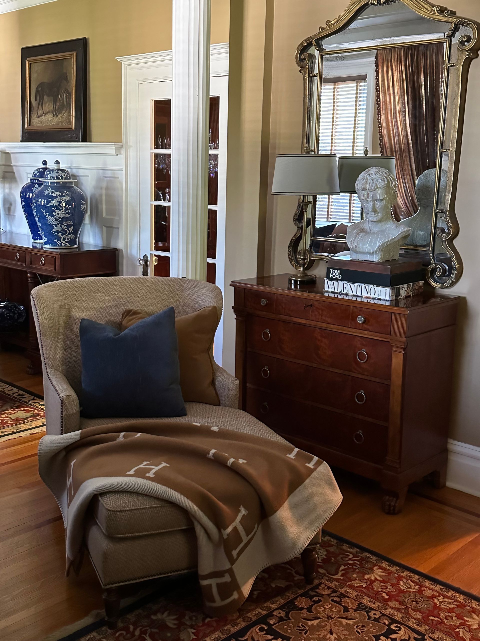 A living room with a chair, dresser, and mirror.