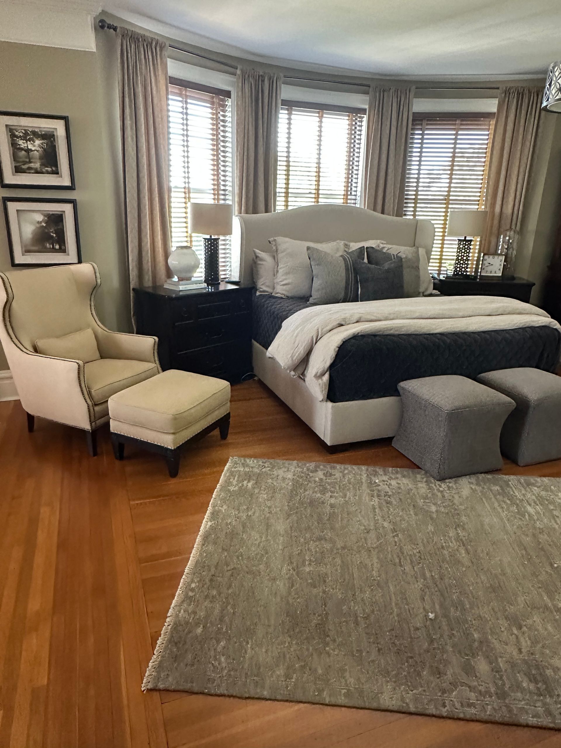 A bedroom with a bed, chair, ottoman and rug.