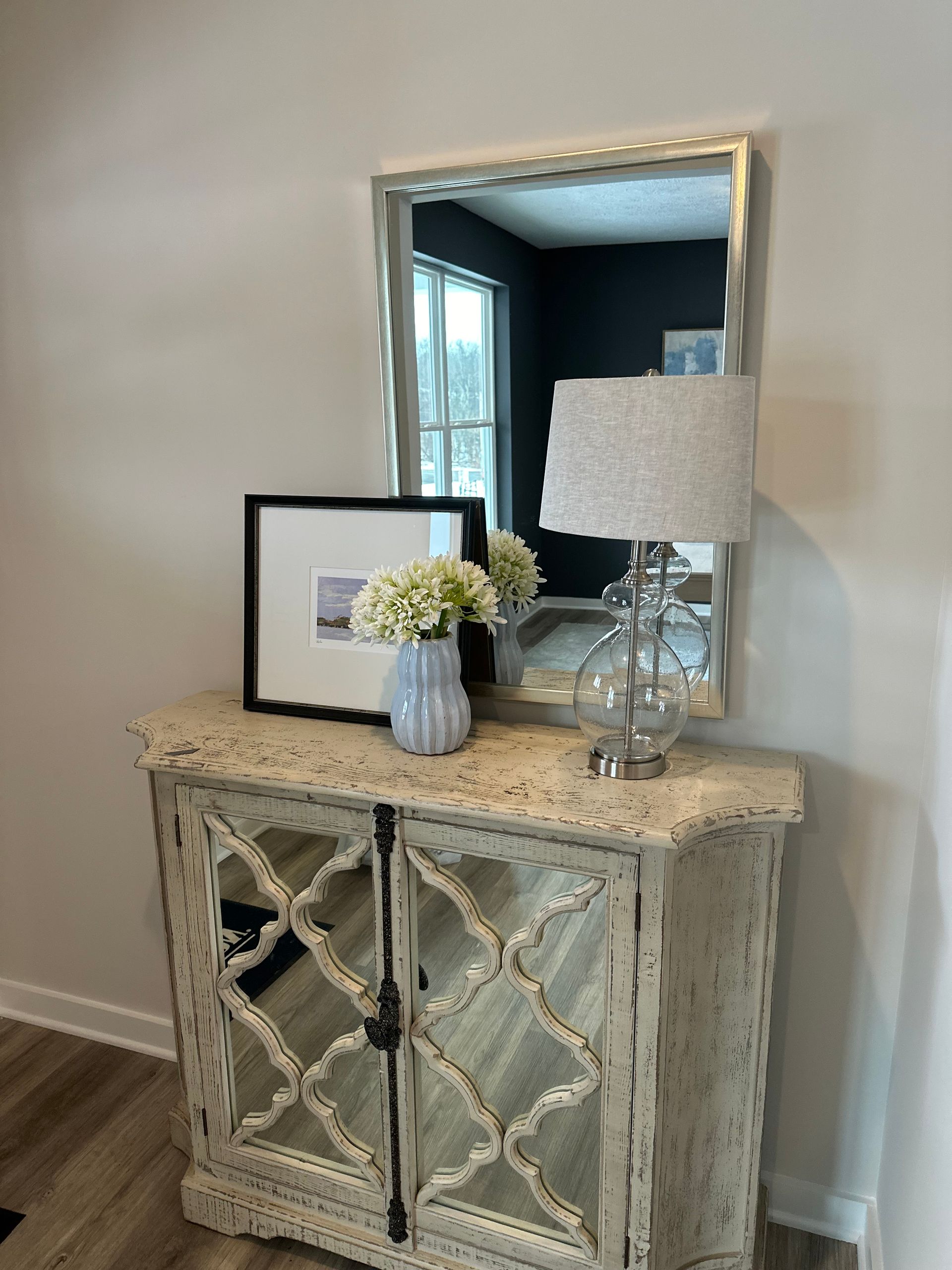 A mirror is sitting on top of a table next to a lamp.