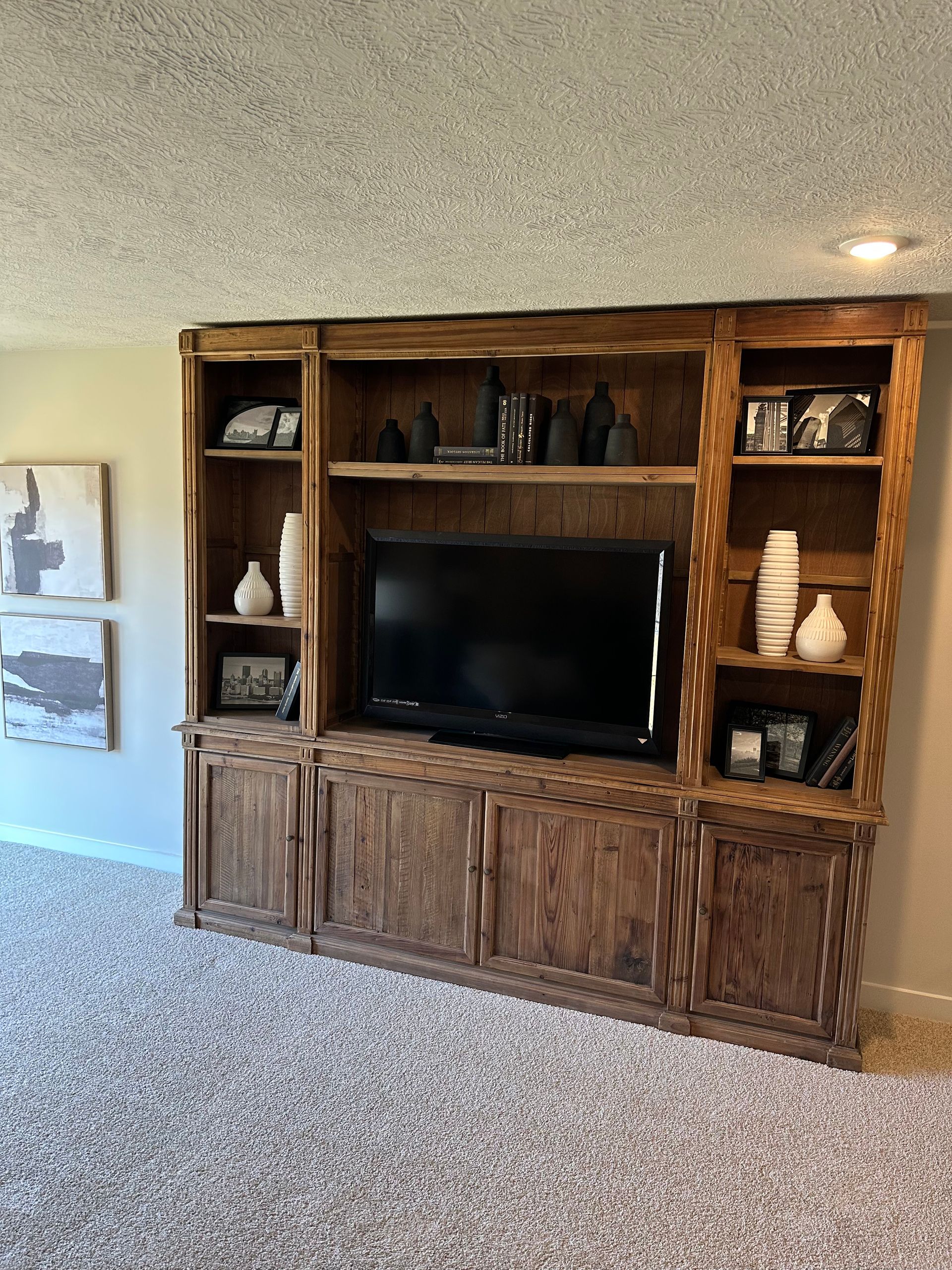 A living room with a wooden entertainment center and a flat screen tv.