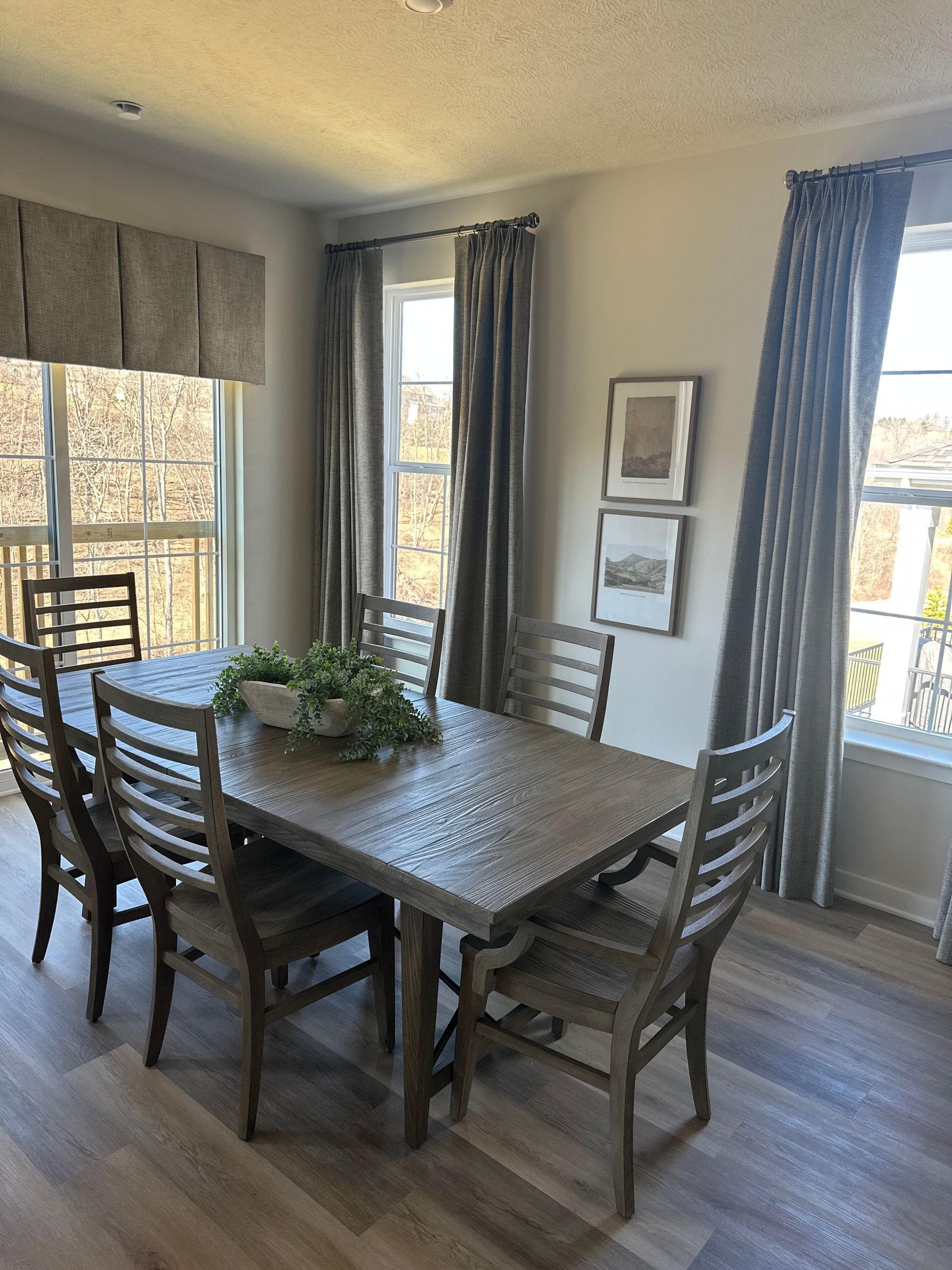 A dining room with a table and chairs in front of a window.
