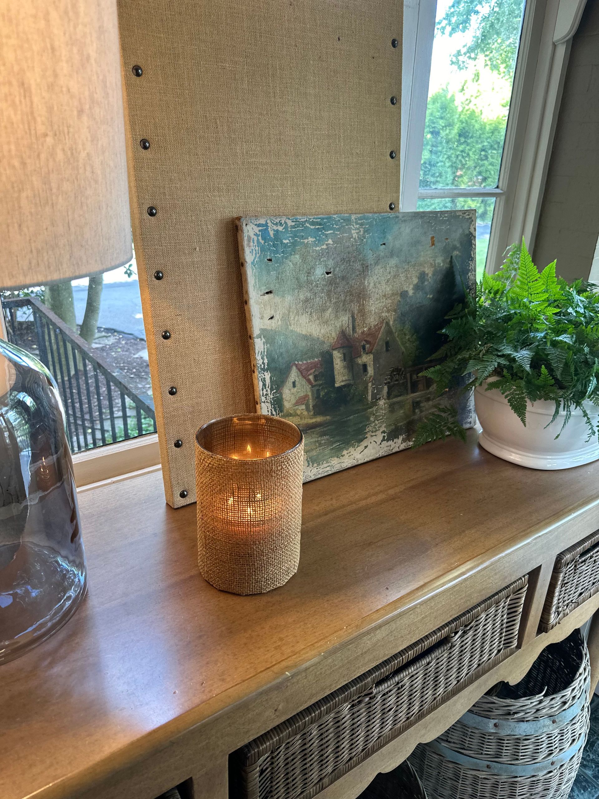 A candle is sitting on a wooden table next to a painting.
