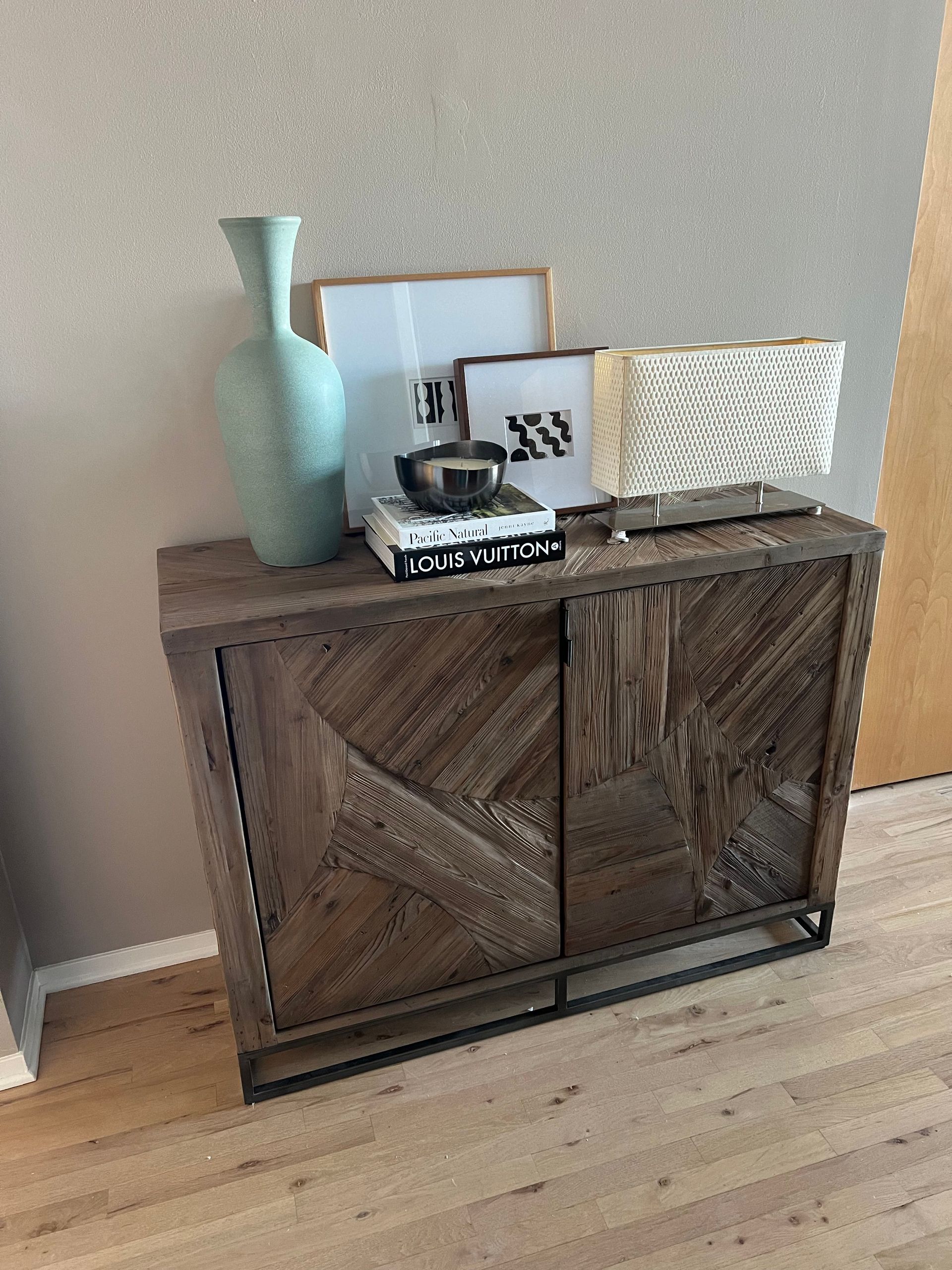 A wooden cabinet is sitting on a wooden floor next to a wall.