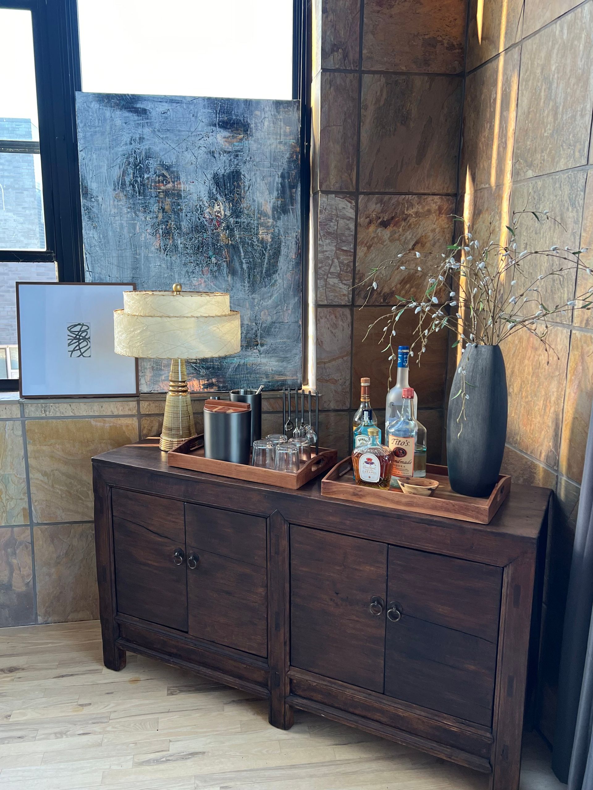A wooden dresser with a lamp and bottles on it.