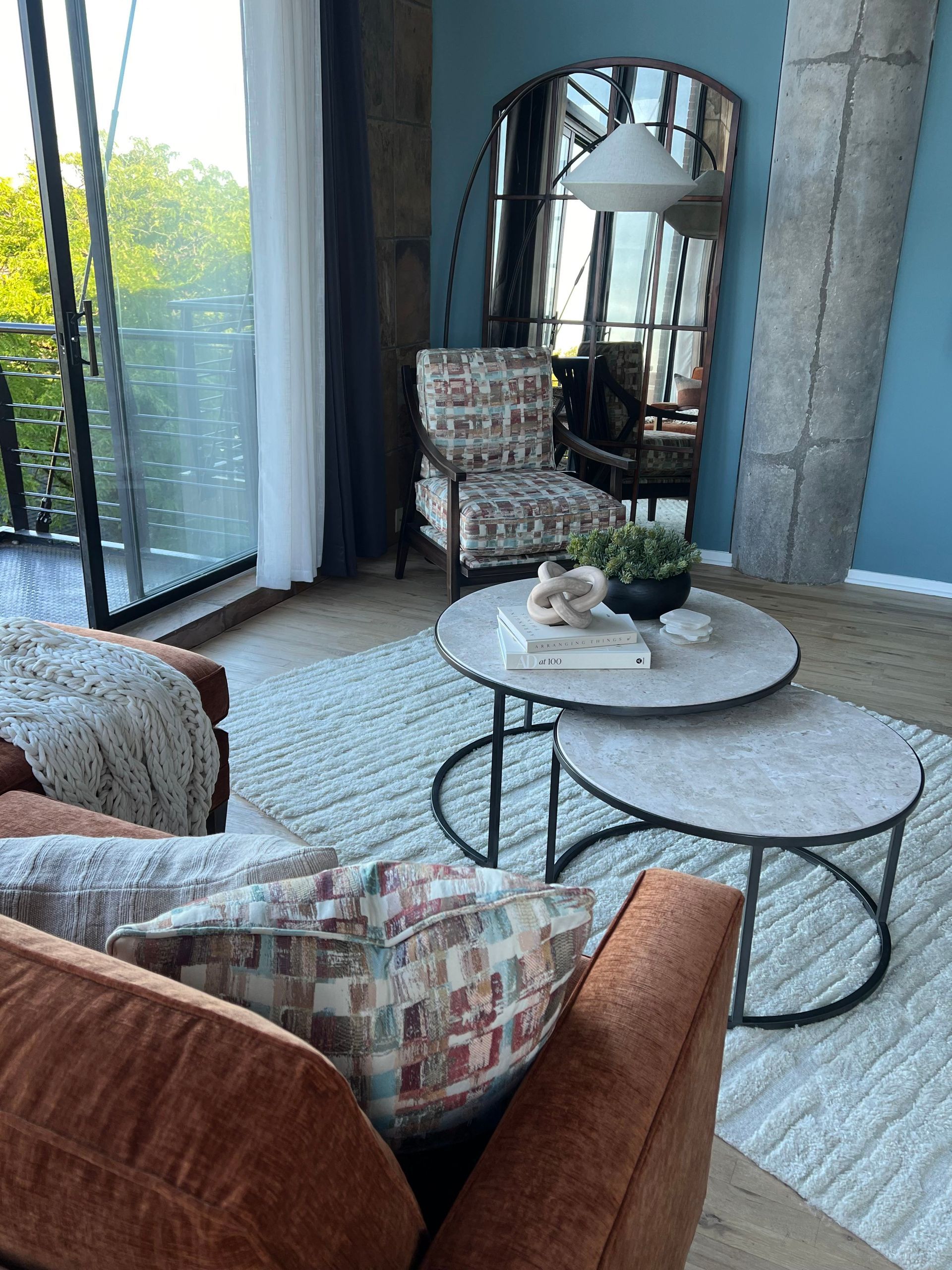 A living room with a couch, chair, coffee tables, and a large mirror.