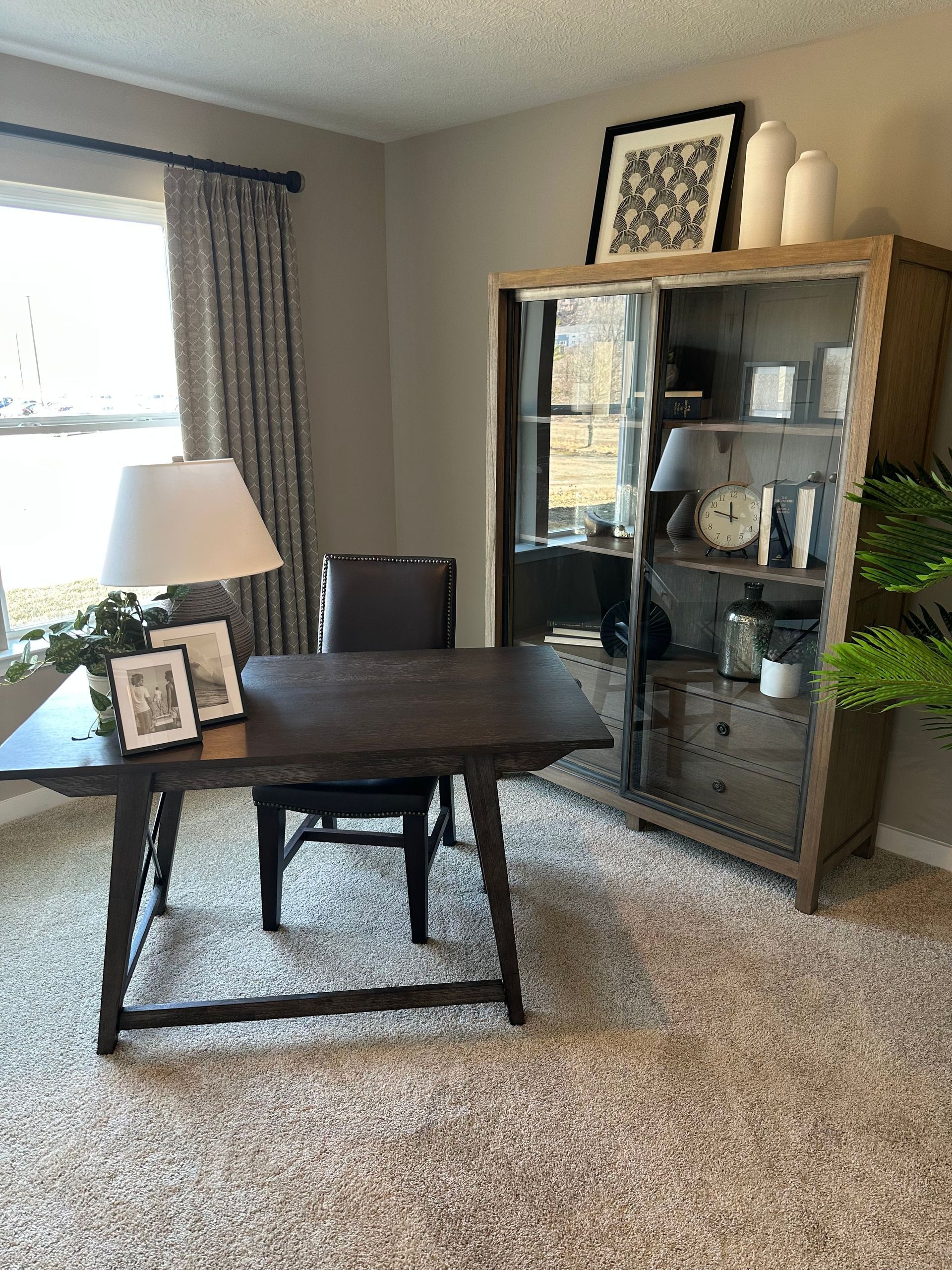 A home office with a desk, chair, lamp, and bookshelf.