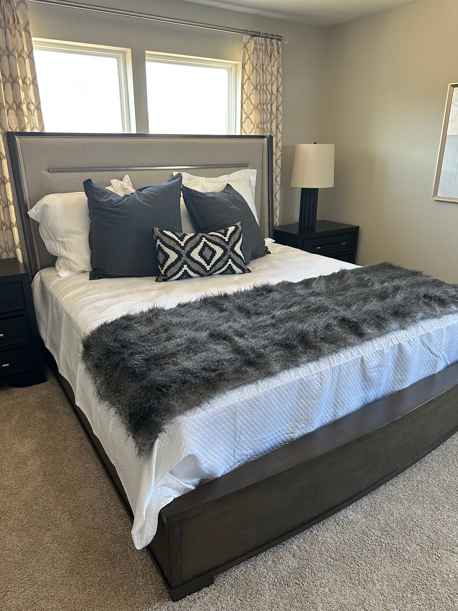 A bedroom with a bed, nightstand, lamp, and window.