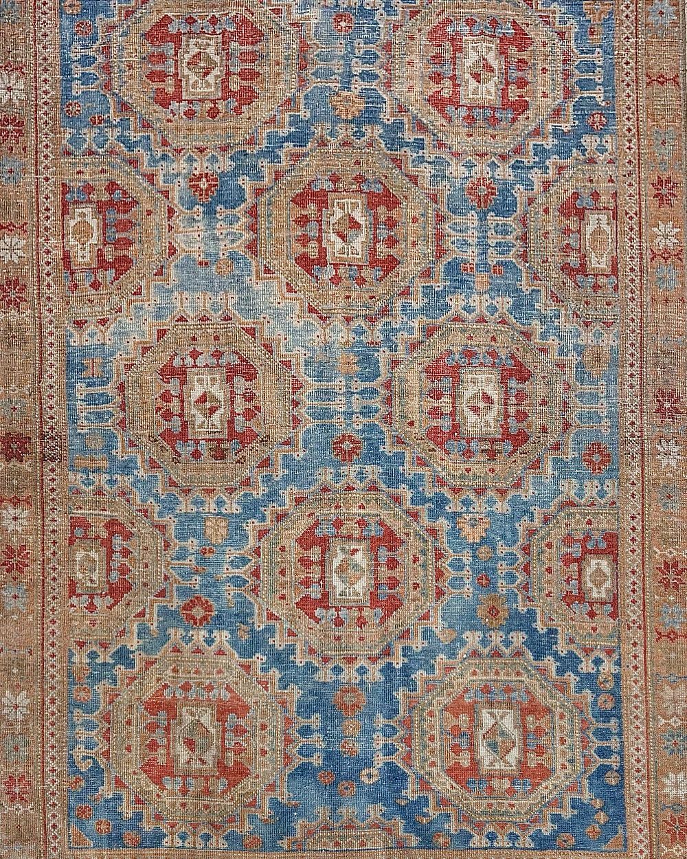 Blue and tan patterned rug with red details; possibly antique.
