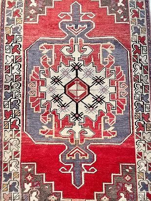 A close up of a red rug with a geometric pattern on it.