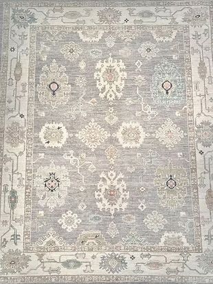 A gray and white rug with a floral pattern on it.