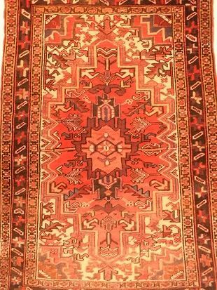 A red rug with a pattern on it is on a white background.