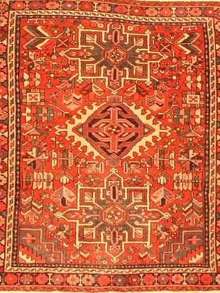 A close up of a red rug with a geometric pattern on it.