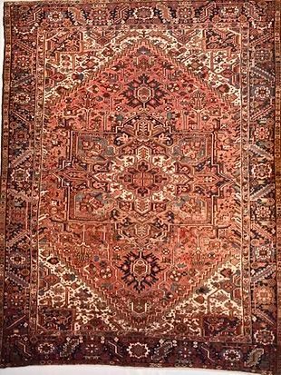 A rug with a pattern on it is hanging on a wall.