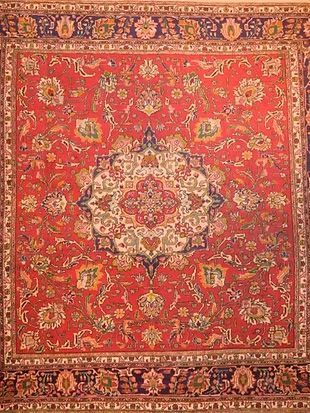 A close up of a red rug with a floral pattern on it.