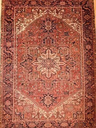 A rug with a pattern on it is hanging on a wall.