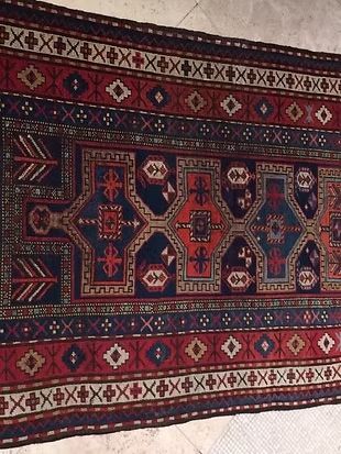 A rug with a geometric pattern is sitting on a tiled floor.