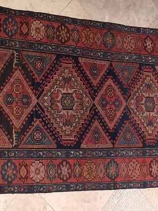 A rug with a pattern on it is sitting on a tiled floor.