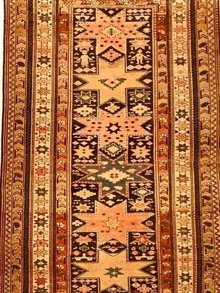 A rug with a geometric pattern on it is on a white background.