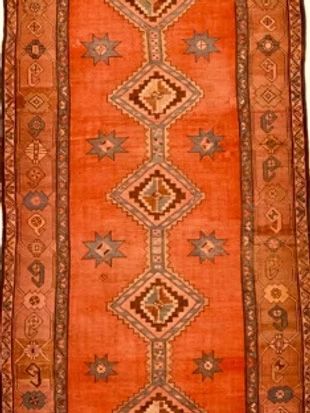 A long orange rug with a geometric pattern on it